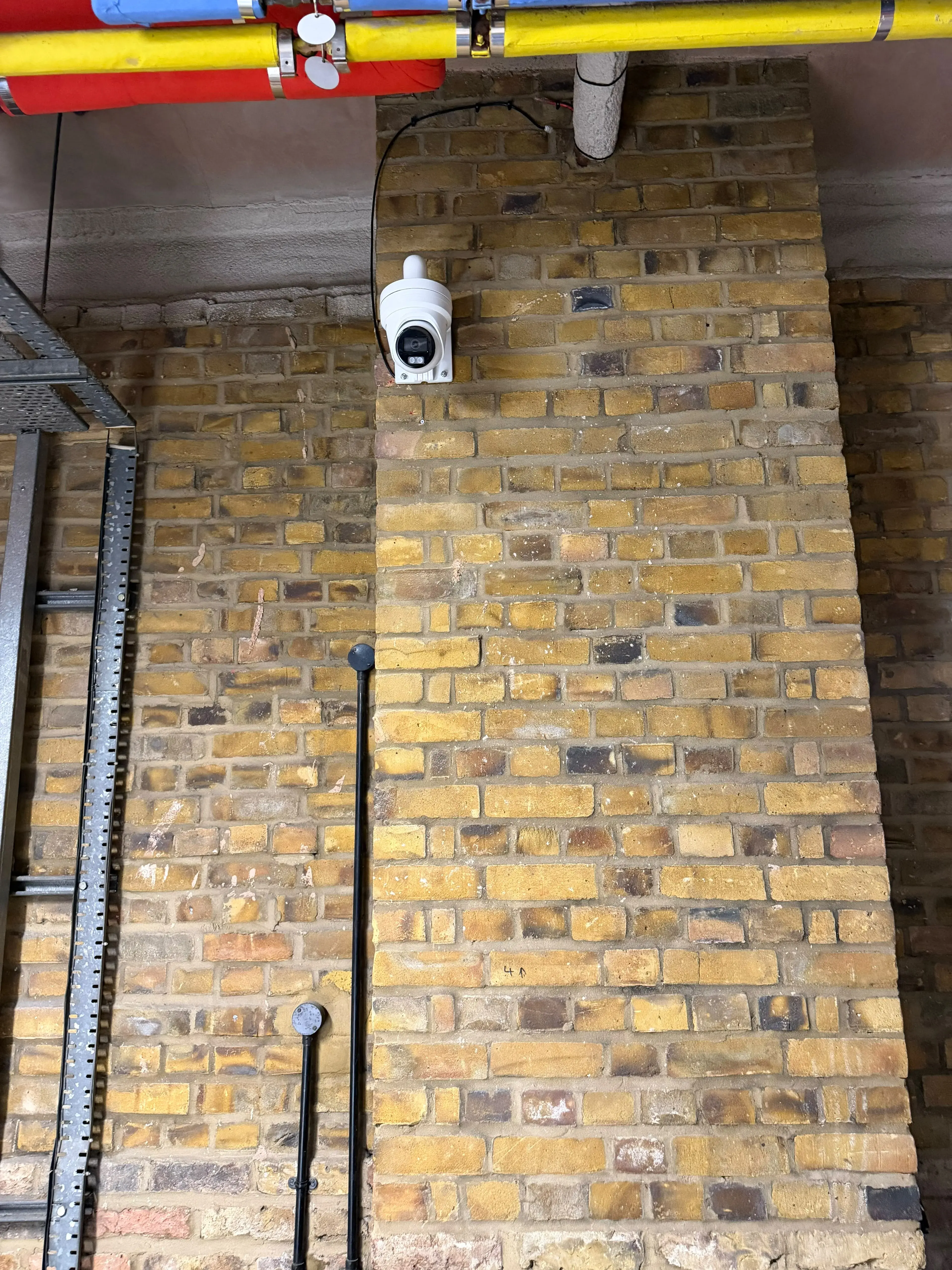 CCTV camera mounted high on an industrial brick wall