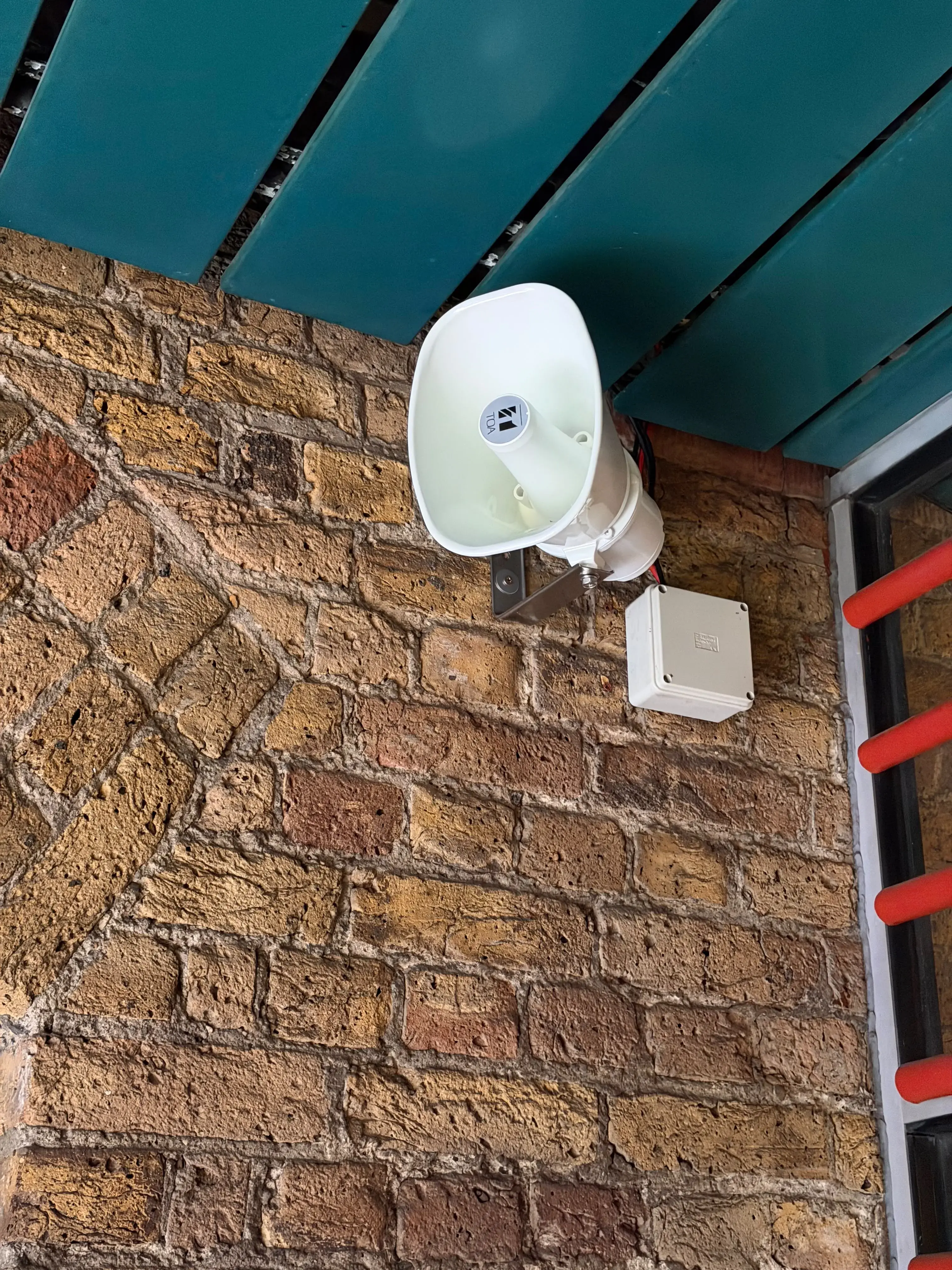 Outdoor warning speaker mounted on a brick wall